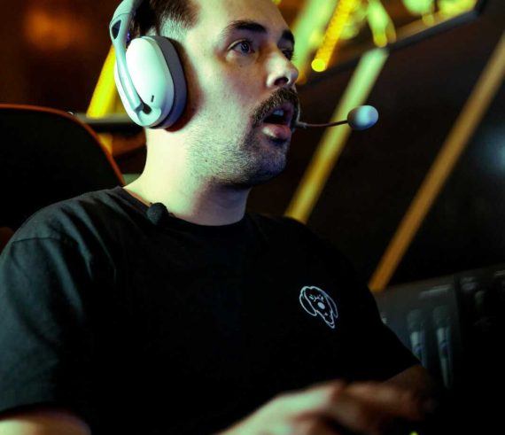 A gamer intensely engaged in an esports competition, wearing a headset in a dimly lit room.