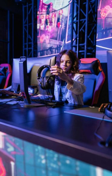 A young woman in a gaming chair adjusting headphones in an esports arena.