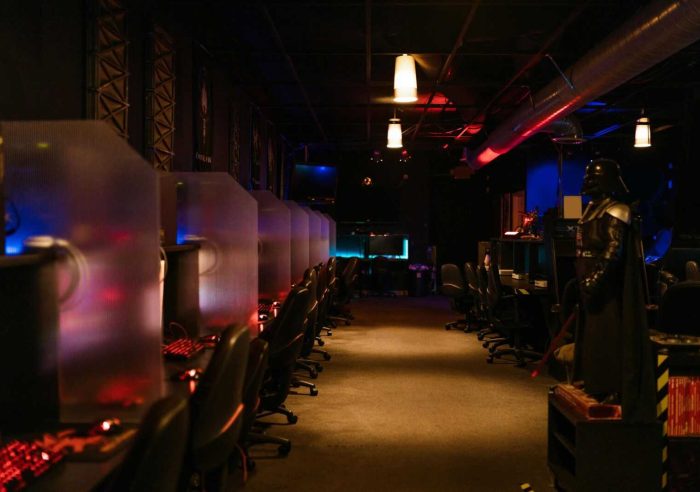 A dimly lit gaming arcade with neon lights and computers, creating a futuristic atmosphere.