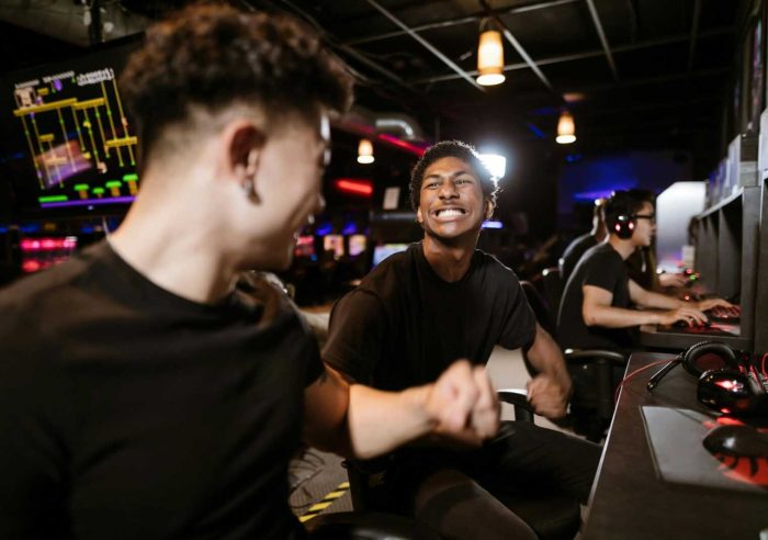 Group of gamers expressing excitement while playing video games in an arcade.