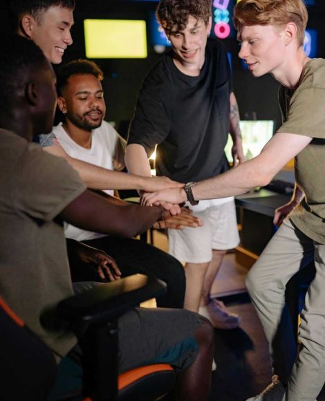 A group of diverse young men celebrating teamwork during a gaming session indoors.