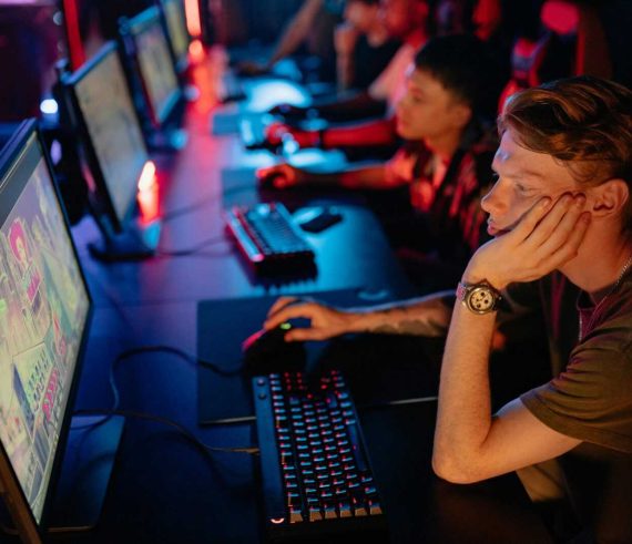 Gamers intensely focused on a computer game during an online esport competition in a dimly lit arena.
